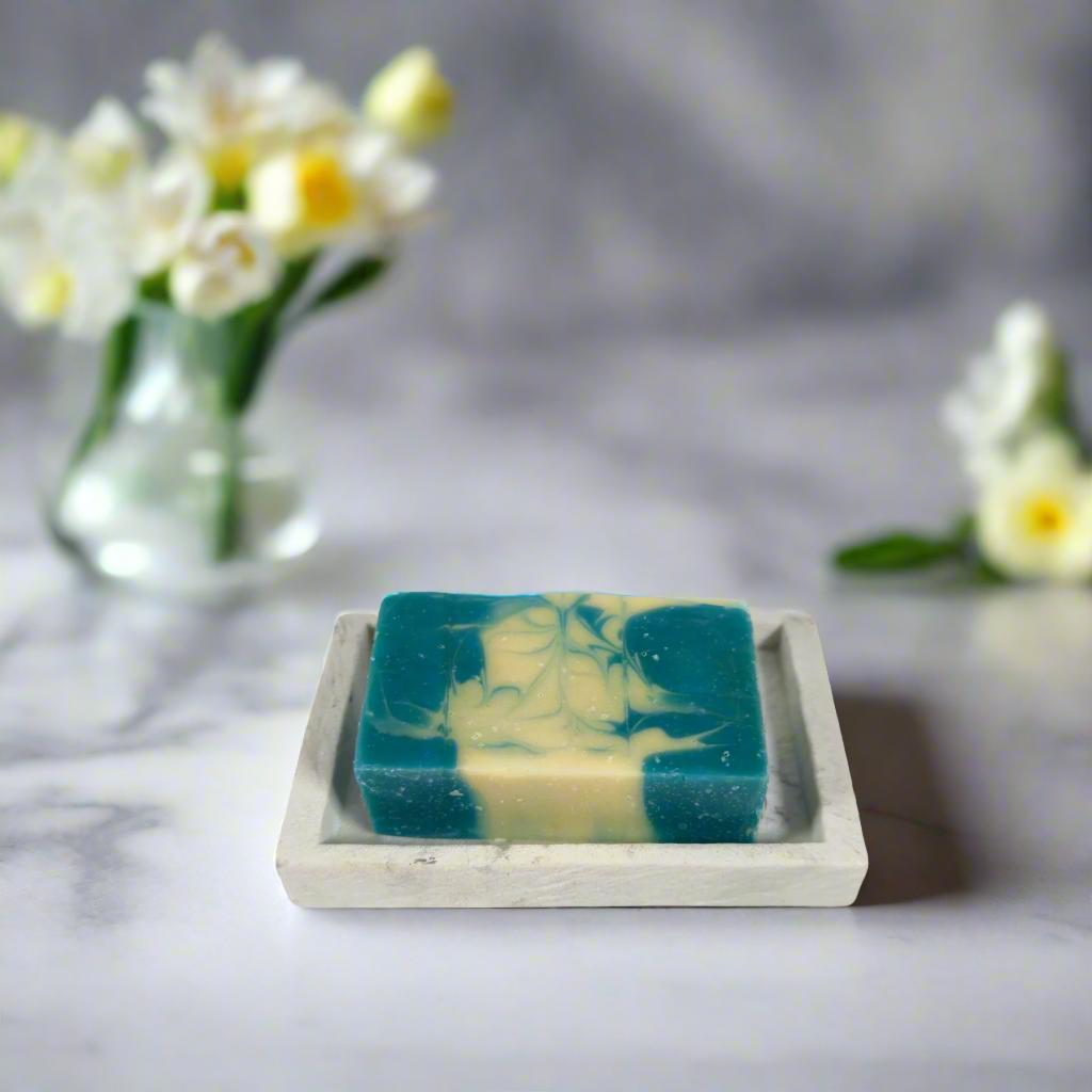 Green and yellow soap bar on a white dish with a blue background