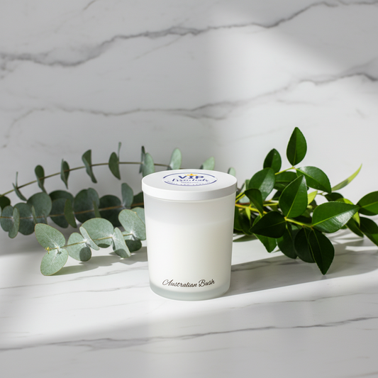 Candle with a white lid and label on a marble surface with green leaves.