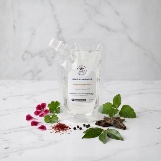 A clear stand-up pouch of V&P Vessels Black Rose & Oud Seed Diffuser Buffer with a white label, styled on a white marble surface with rose petals, green leaves, cinnamon, and saffron.