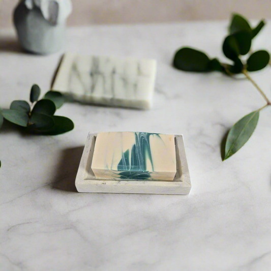 Marble-patterned soap bars on a marble surface with green leaves.