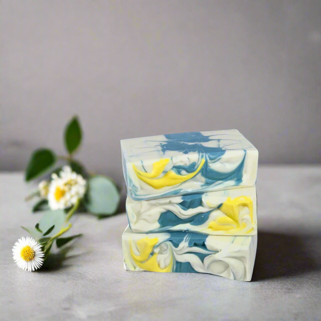 Stack of soap bars with blue and yellow swirls on a gray surface with flowers.