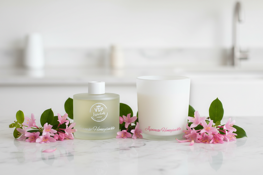 Frosted bottle and white candle with 'Japanese Honeysuckle' branding on a blue background