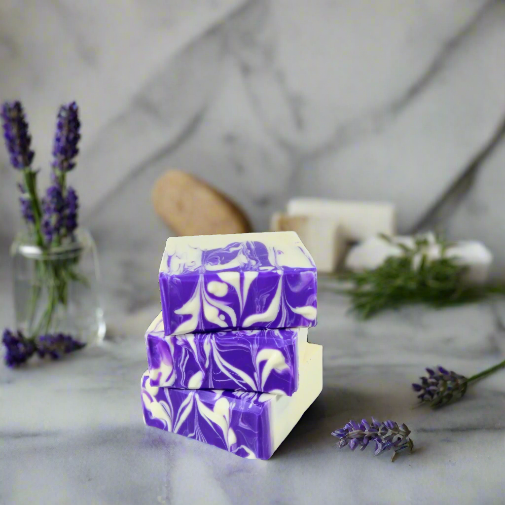 Stack of purple and white marbled soap bars on a marble surface with lavender flowers.