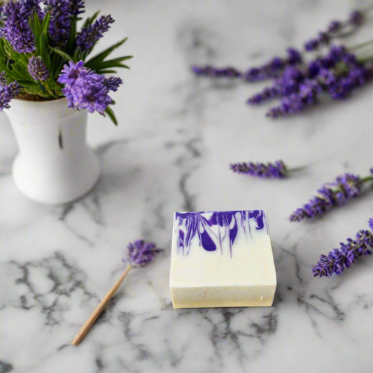 Bar of soap with purple design on a marble surface with lavender flowers