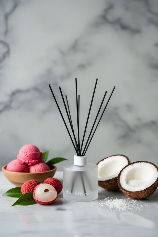 Reed diffuser with black sticks on a marble surface with red and white flowers.