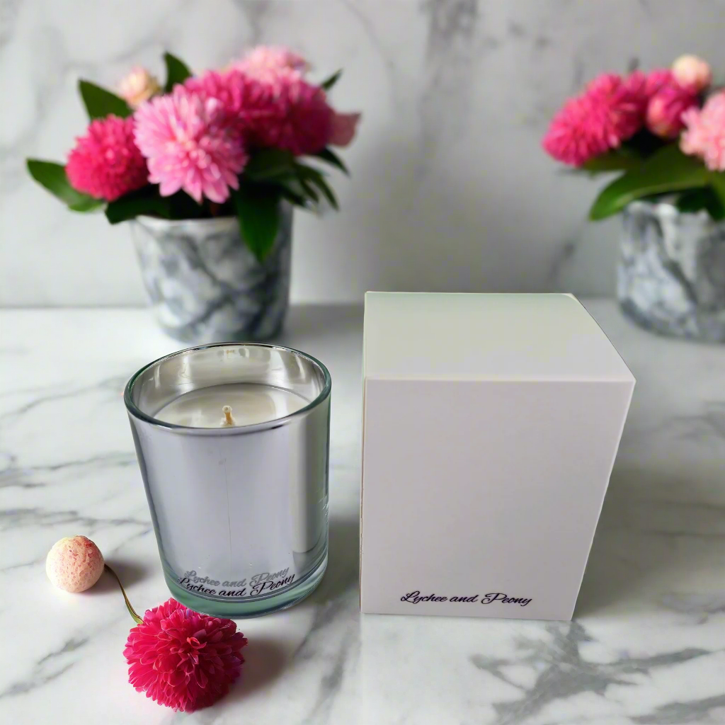 Glass candle with a white wick next to a white box on a white background