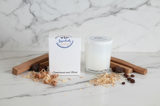 White candle with 'VIP Essentials' branding next to its packaging on a white background