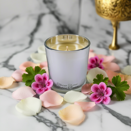Candle in a glass holder on a marble surface with a gold decorative object in the background