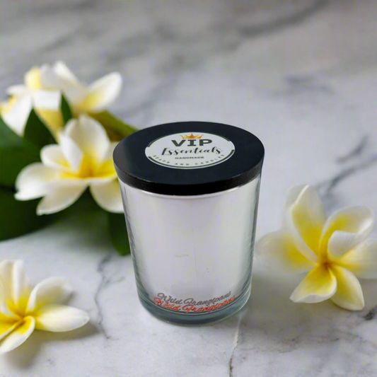 Clear glass candle with black lid and label on a white background