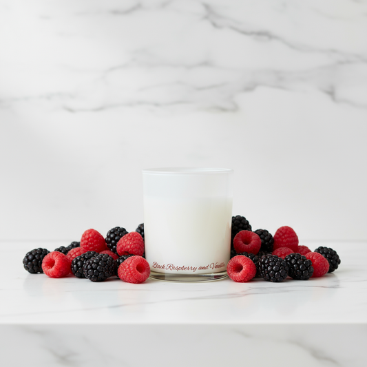 White candle with raspberries and blackberries on a marble surface