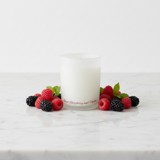 A frosted glass candle jar with a white wax fill and a single wick, featuring red script text near the bottom that reads 'Raspberry and Vanilla'.