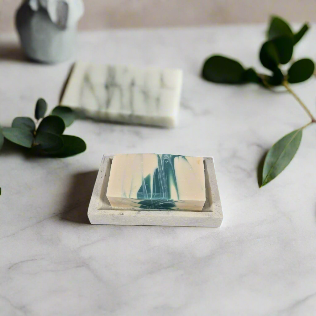 Marble-patterned soap bars on a marble surface with green leaves.