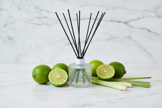 Reed diffuser with black sticks in a clear bottle on a blue background