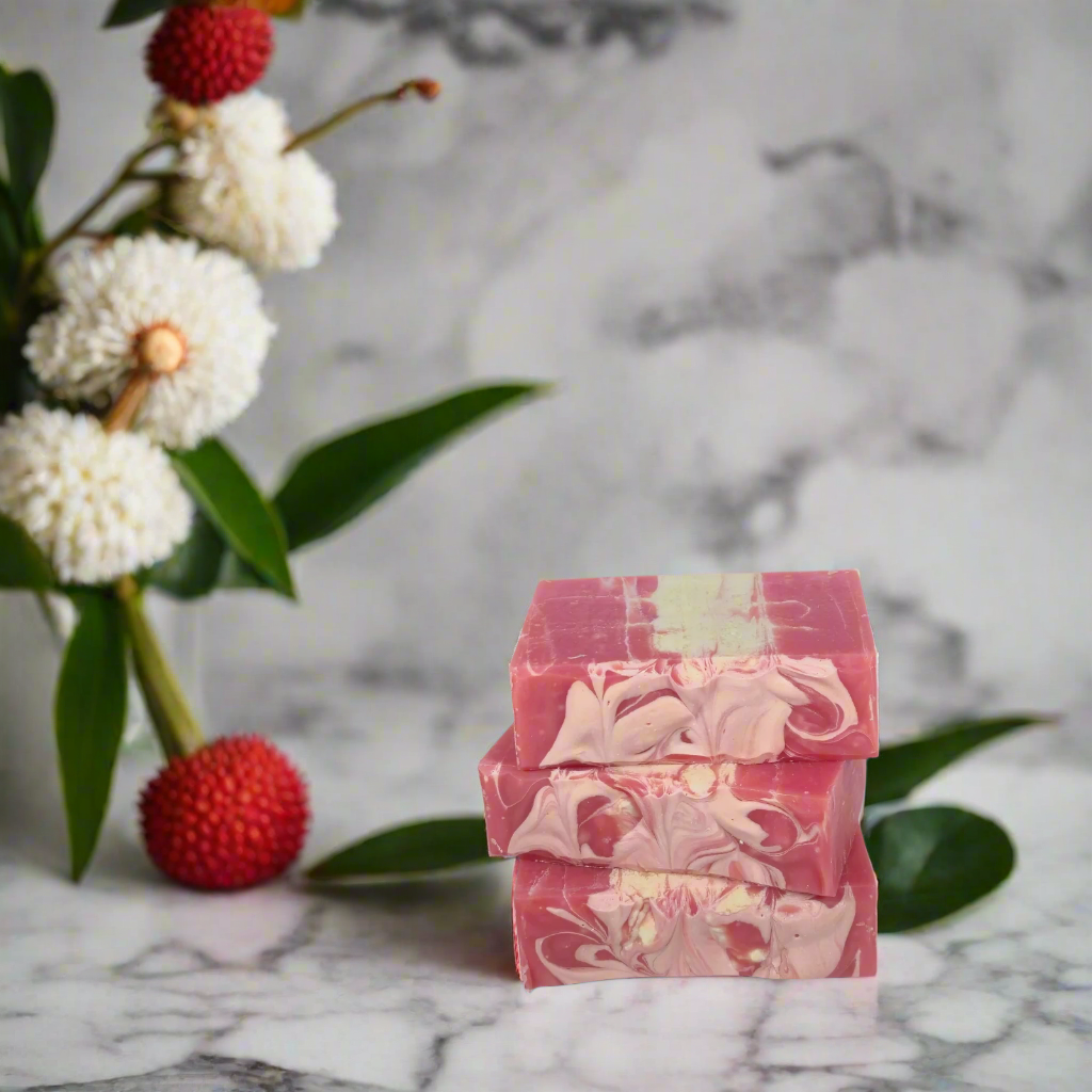 Stack of pink and white marbled soap bars on a marble surface with flowers in the background