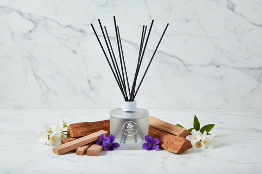 Reed diffuser with black sticks in a clear bottle on a blue background