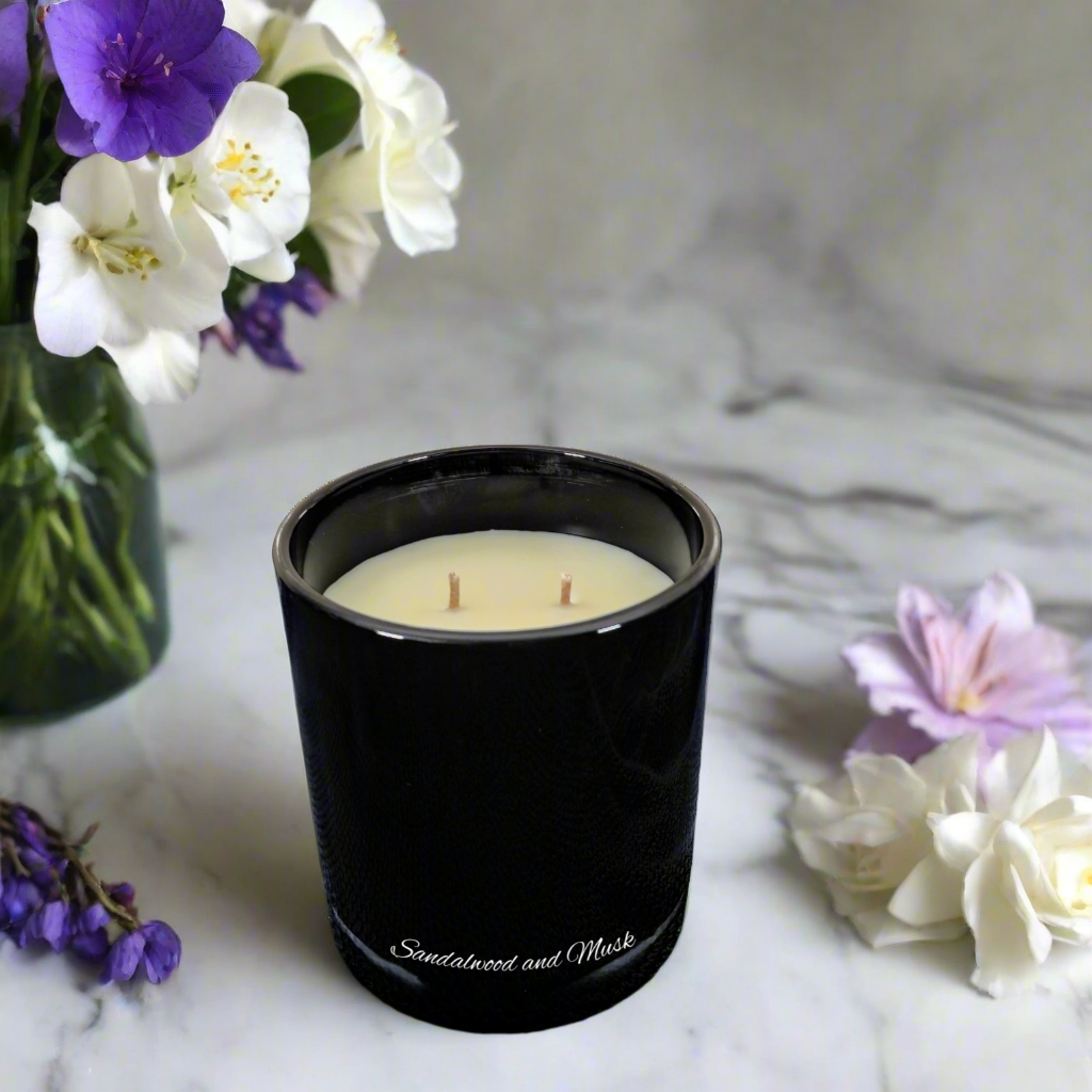 Black candle with floral arrangement on marble surface