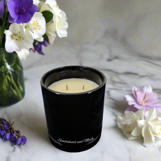 Black candle with floral arrangement on marble surface