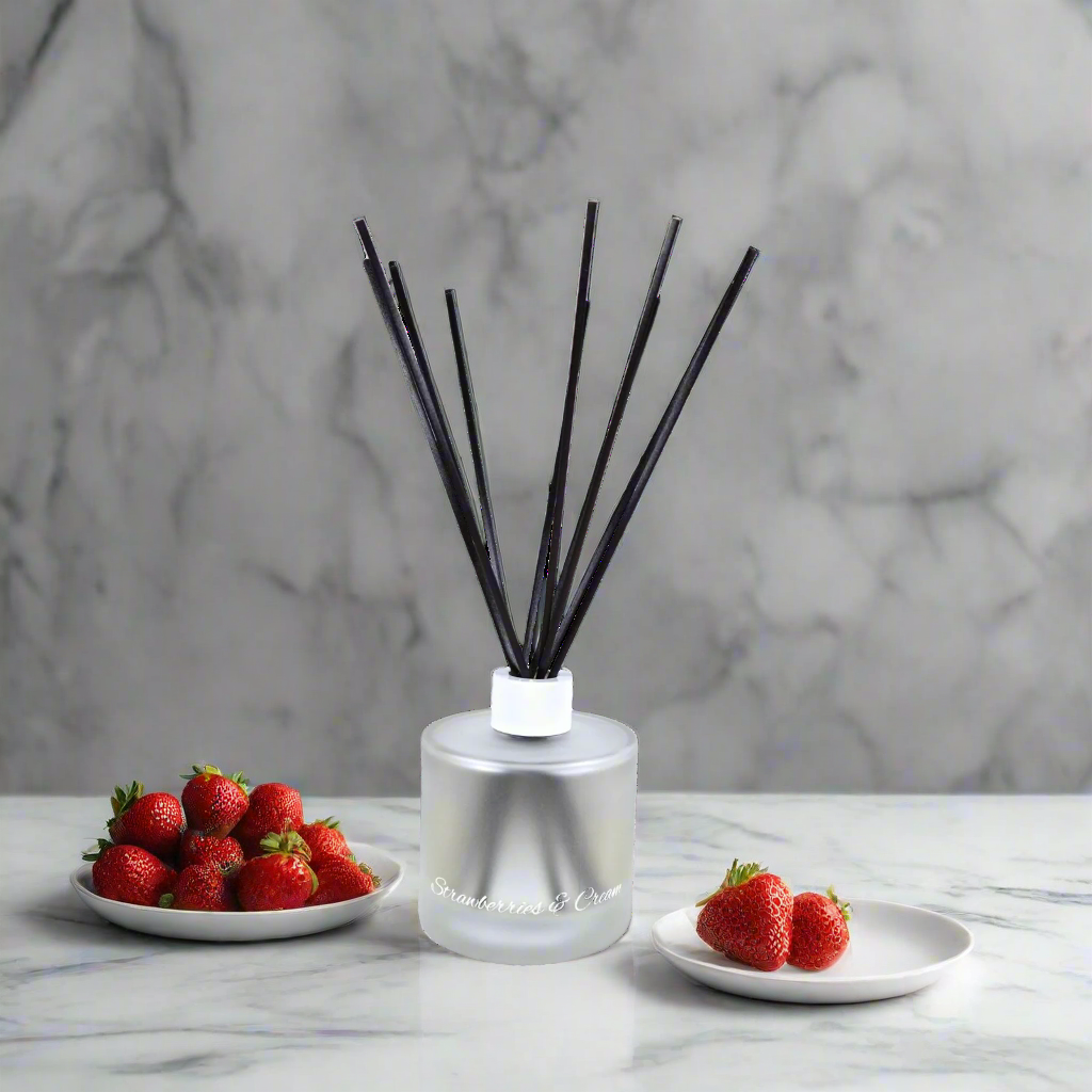 Reed diffuser with black sticks on a marble surface with strawberries