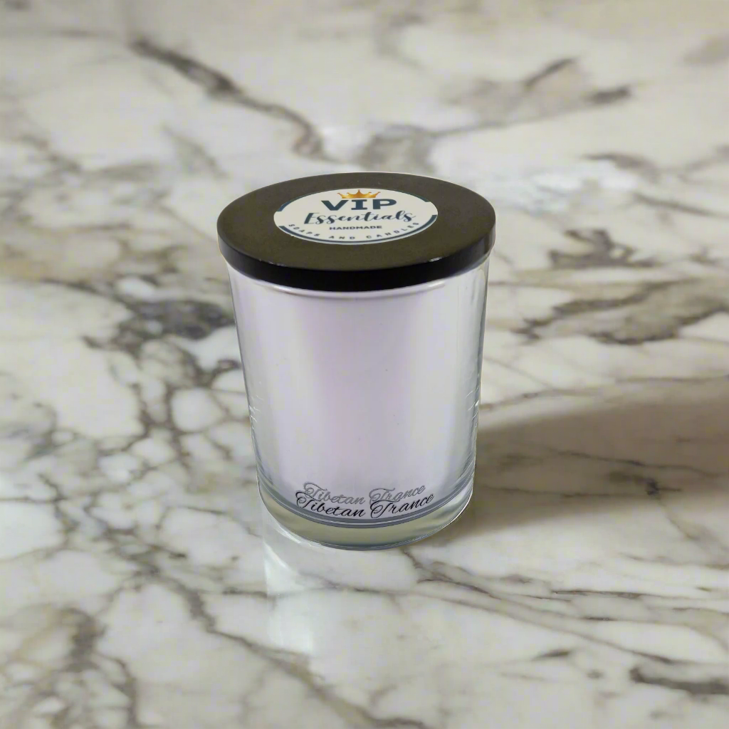 Clear glass candle with a black lid on a white background